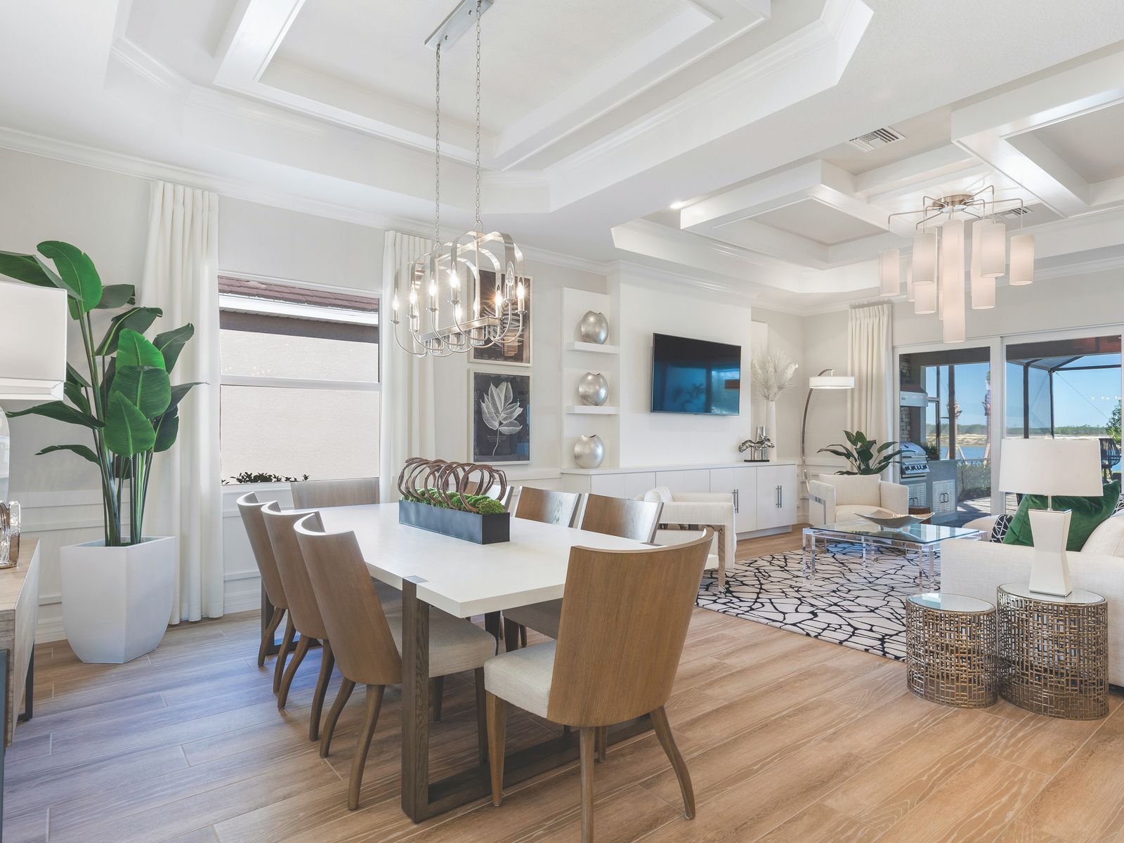 Bright dining and living room with a white coffered tray ceiling, crown molding and a lantern chandelier