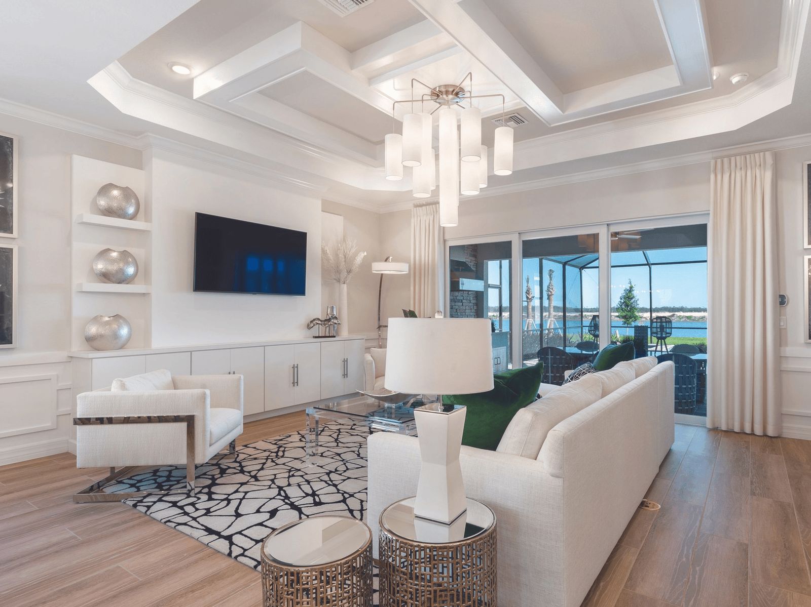White coffered ceiling with recessed panels and a crystal chandelier over a bright living room